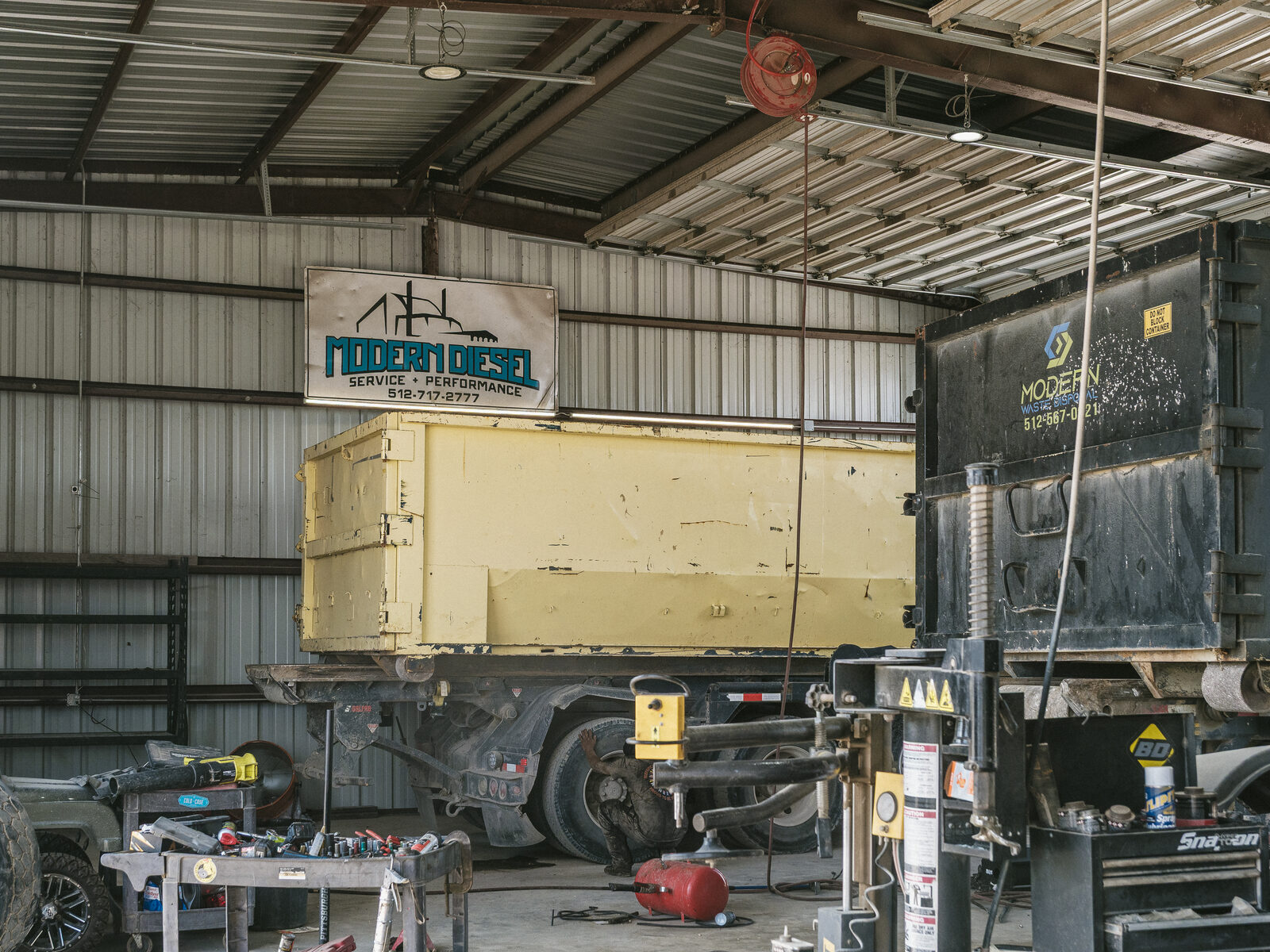 Roll-off truck and container in the shop under the Modern Diesel sign