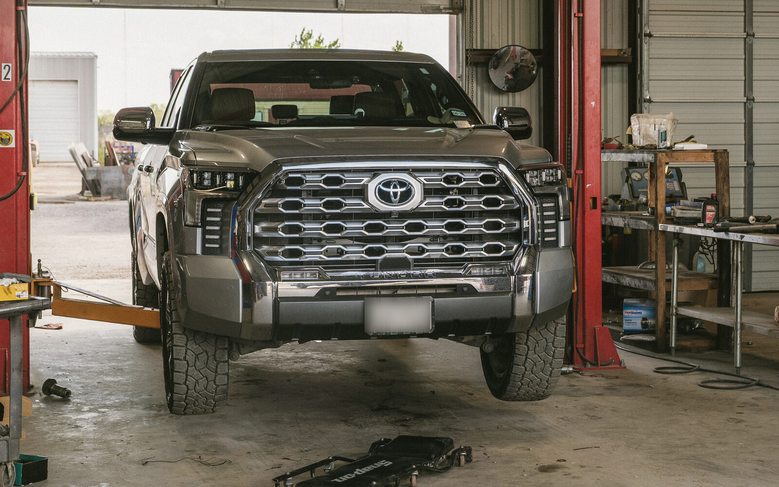 Toyota Tundra on all-terrain tires up on a two-post lift in the Modern Diesel shop