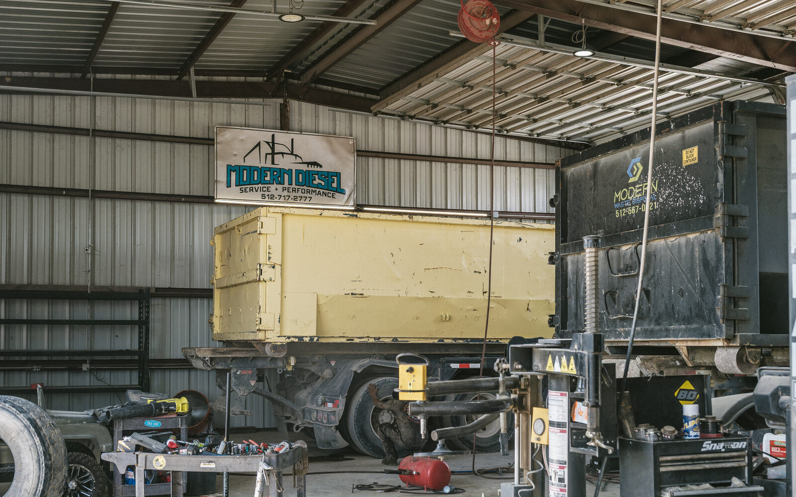 Roll-off truck and container in the Modern Diesel shop under the Modern Diesel sign
