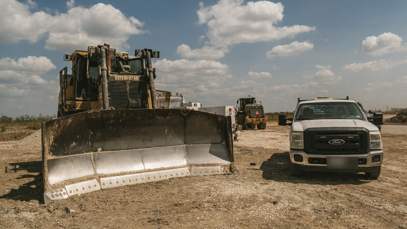 Cat D9 dozer blade on a job site, with the Modern Diesel service truck parked behind it